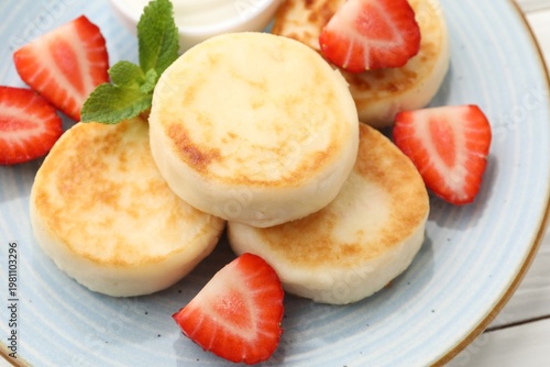 Delicious cottage cheese pancakes with strawberries and mint on plate, closeup