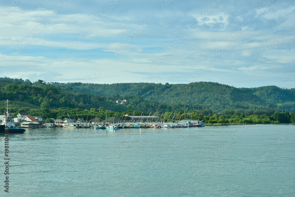 Fototapeta premium Wide coastal view of Kampung Nelayan Tradisional di Bakauheni, Selat Sunda, Lampung, Indonesia. Ideal for travel, marine industry, and banner background.