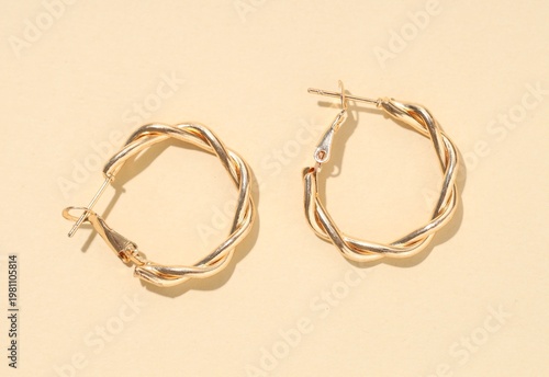 Φωτογραφία Pair of golden earrings on beige background, flat lay