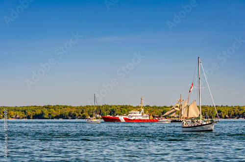 Coast Guard ship sailing past two sailboats
