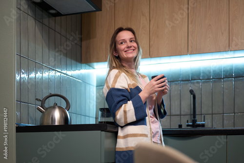 Female standing in kitchen holding cup near counter