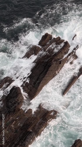 Wallpaper Mural Ocean waves powerfully crashing against jagged coastal rocks creating white sea foam during the day. Torontodigital.ca