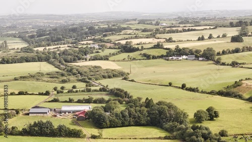 Wallpaper Mural Panoramic view over the beautiful Irish countryside with rolling green fields, traditional farms, and winding paths. White farmhouses and barns dot the lush landscape under bright daylight. Torontodigital.ca