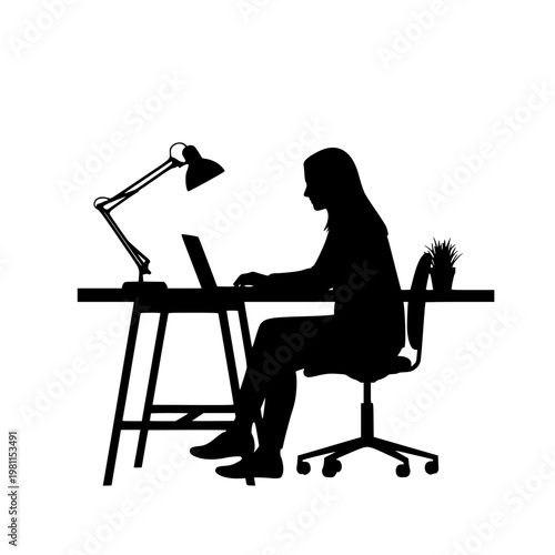 Person working on laptop at a well-lit desk with a desk lamp and plant nearby