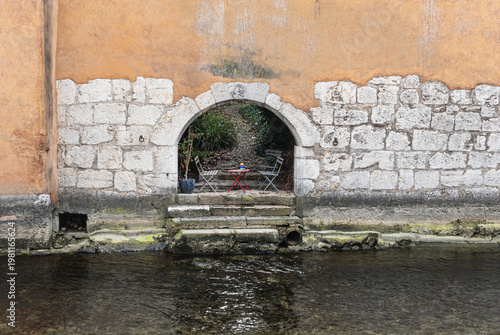 Chairs and table under archway in ancient wall at the river Le Thiou in Annecy France