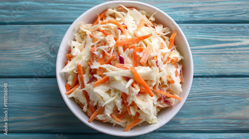 Delicious coleslaw in a white bowl on blue wooden table