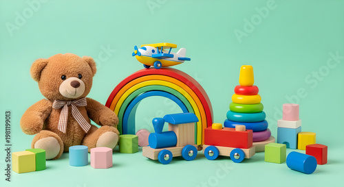 Colorful children's toys and teddy bear arranged on green background including train