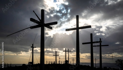 Silhouetted crosses on a hilltop against a dramatic, cloudy sky with sunbeams breaking through