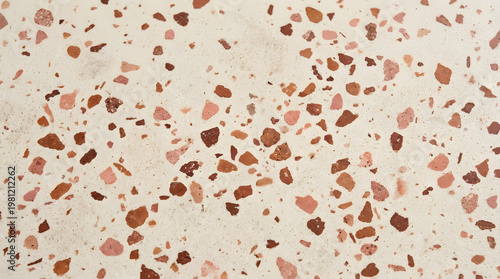 A close-up texture of speckled terrazzo flooring in warm earth tones, showcasing its unique composite material and decorative aggregate pattern