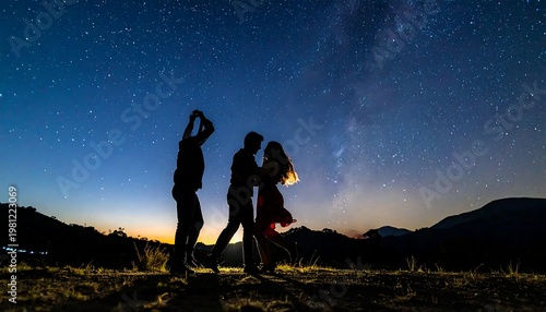 Silhouetted figures dance in a field under a dark, star-filled sky with mountains on the horizon