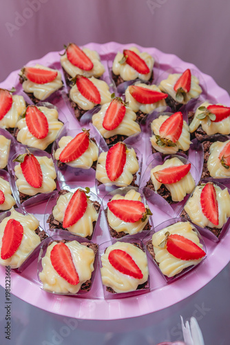 Gourmet Chocolate Brownie Bites with Cream and Fresh Strawberry Slices on Party Tray Close Up Birthday Dessert Table Sweet Treats