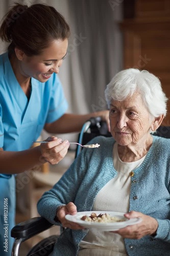 A kind nurse in blue scrubs smiles while spoon-feeding an elderly woman with white hair in a wheelchair. The scene, with soft lighting warm tones, depicts caring assistance daily living support