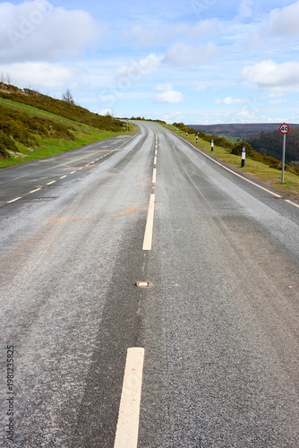 Two lane road with highway markings rising to horizon with fair sky