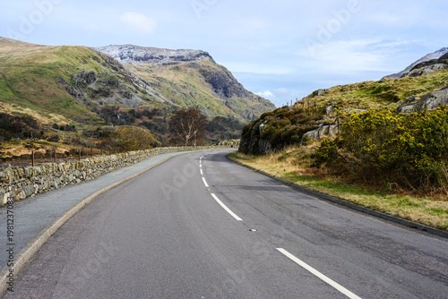 Welsh road winds through rugged snow dusted landscape of Eryri Snowdonia National Park