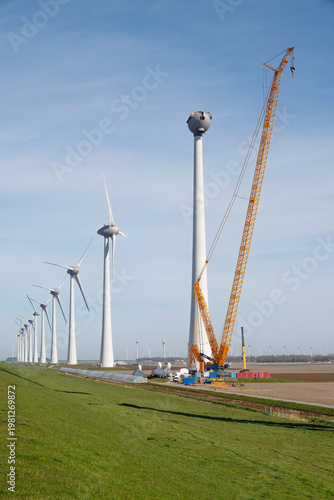 Wind turbines under construction with crane in polder landscape