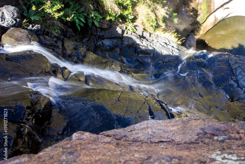 Looking down at a waterfall where it flows down to a secluded pool below, in the remote regions of the Drakensberg Mountains of the Golden Gate Highlands National Park, South Africa.