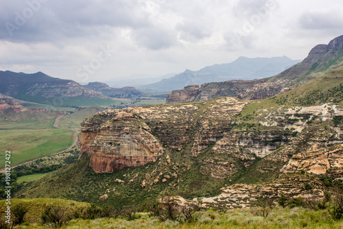 Storm clouds gathering over a valley surrounded by cliffs and distant blue mountains in the Drakensberg Mountains of the Golden Gate Highlands National Park, South Africa