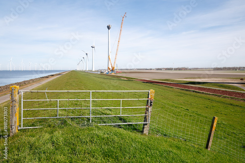 Wind turbines along dike with fence and perspective