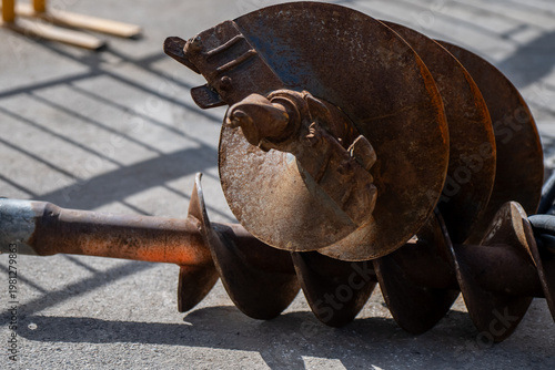 Foto Rusted earth auger drill bit with helical flights and cutting head lying on pave