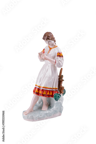 Vintage Porcelain figurine of a barefoot girl standing on the ground, fortune telling with a daisy flower. Ceramic statue of a girl wearing Ukrainian traditional dress isolated on white.
