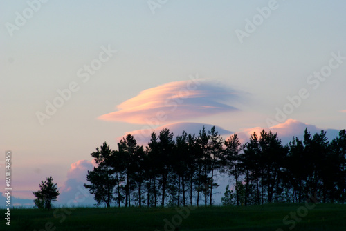 Clouds form over trees during sunset in a rural area of the countryside