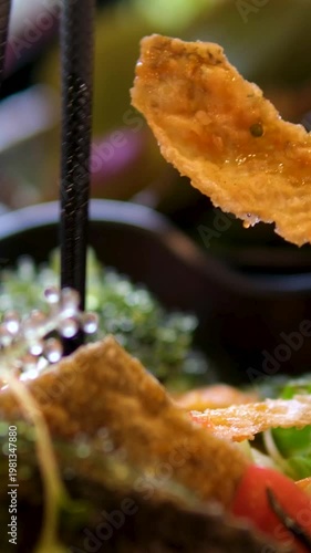 Asian salad with caviar picking tortilla chip with chopsticks adding fish roe elegant seafood appetizer close-up black plate