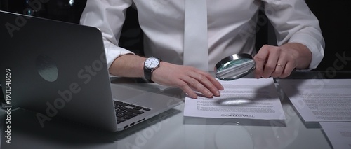 Photos Businessman examining a document using a magnifying glass, focusing on fine print and terms in a legal agreement, working late