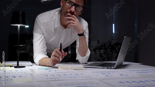 Photos Dedicated businessman intensely analyzing financial documents and charts spread