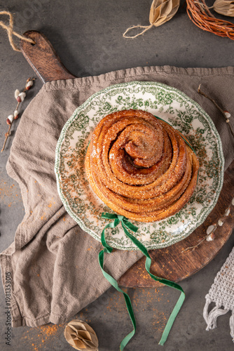 Wallpaper Mural Top view of a sweet flaky Easter bread roll dusted with sugar on a vintage plate styled with a green velvet ribbon and rustic spring decorations on a grey stone surface Torontodigital.ca