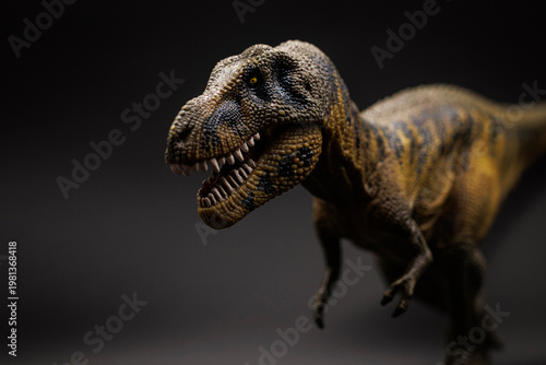 Close-up of a Tyrannosaurus rex toy figure with detailed texture and shallow depth of field, isolated against a blurred neutral background, illustrating prehistoric wildlife and educational toys.