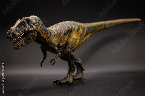 Close-up of a Tyrannosaurus rex toy figure with detailed texture and shallow depth of field, isolated against a blurred neutral background, illustrating prehistoric wildlife and educational toys.
