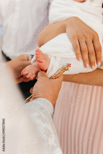 Cuadro en lienzo A close-up of a priest using a golden brush for the holy anointing ritual on a newborn baby's feet during a traditional Orthodox christening