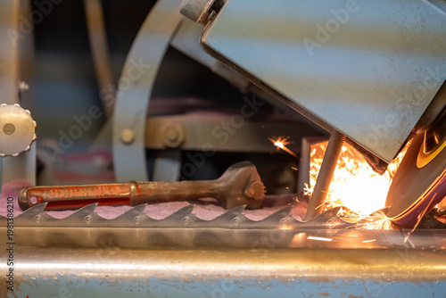 Sparks fly from a grinding machine while shaping metal on a workshop bench