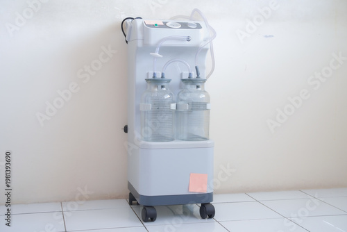 Medical suction machine with graduated collection bottles and vacuum gauge, used for aspirating bodily fluids during surgical procedures