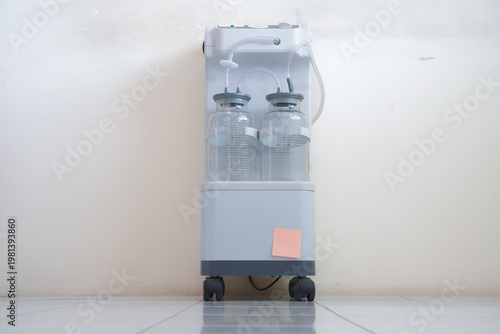 Medical suction machine with graduated collection bottles and vacuum gauge, used for aspirating bodily fluids during surgical procedures