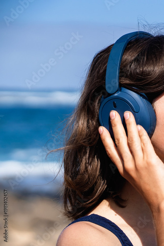 A girl with a wireless headphones, is listening music outdoors.