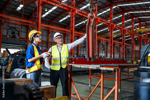 Obraz na plátně A male chief engineer is instructing female workers on operating machinery in a large factory