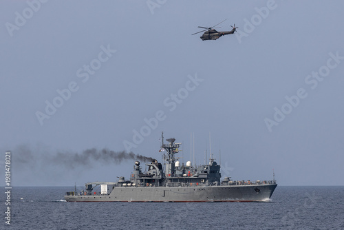 A helicopter flies over a warship during a naval exercise in mediterranean sea.