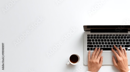 Person typing on a portable computer beside a cup of dark beverage on a clean white surface
