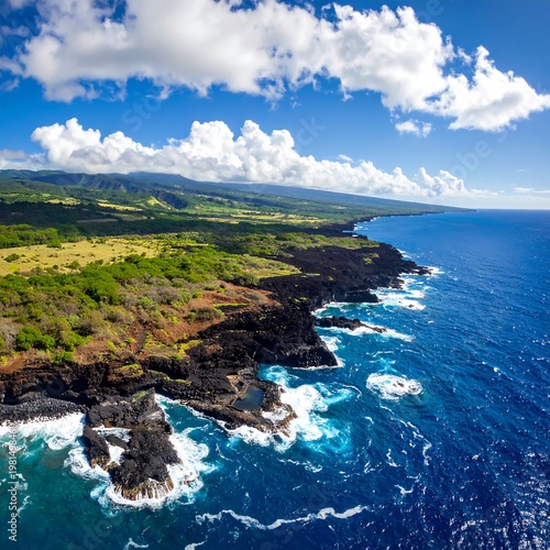 Aerial view of rugged coastline with waves crashing against rocks under blue sky