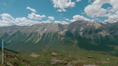 Scenic summer mountain landscape with dramatic rocky peaks, green forest valleys, and blue sky with clouds. View from a hiking trail overlooking the Canadian Rockies, capturing nature, adventure, and 