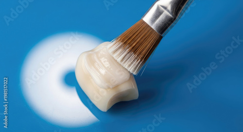 Dental veneer application with a brush on a blue surface for cosmetic dentistry and tooth restoration procedures in a studio setting