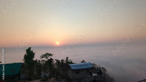 A serene video of a sunset over a foggy landscape with trees and buildings