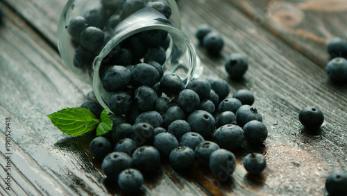 Foto closeup fresh appetizing blueberry scattering out of glass jug on wooden desk