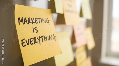 Marketing is everything written on yellow sticky note attached to glass surface in creative workspace.