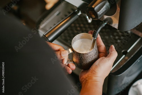 Canvas Print Barista steaming milk in stainless steel pitcher for coffee latte
