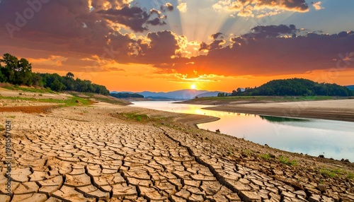 Cracked earth landscape with a river and dramatic sunset sky