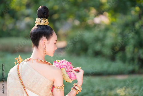 Thai Woman in Traditional Costume Holding Pink Lotus, Elegant Cultural Portrait.
