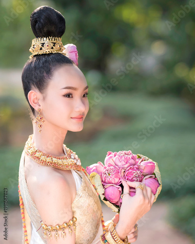 Thai Woman in Traditional Costume Holding Pink Lotus, Elegant Cultural Portrait.
