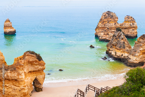 Yellow sandstone rocks and turquoise water on the coast of Atlantic ocean in Algarve, Portugal. Beautiful seascape at foggy morning.